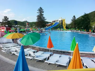 a large swimming pool with chairs and umbrellas at Hiška Marjetica in Podčetrtek
