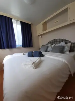 a large white bed in a room with blue curtains at Edenski vrt in Ivančna Gorica