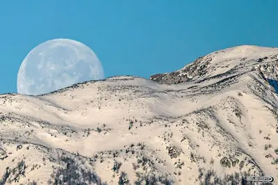 a moon over a mountain with snow on it at Natur pur Pikovo in Črna na Koroškem