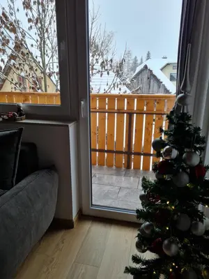 a christmas tree in a living room next to a window at Apartments Gaby in Gozd Martuljek