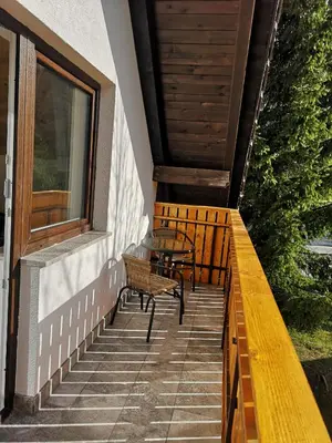 a porch with two benches and a table and a window at Apartments Gaby in Gozd Martuljek