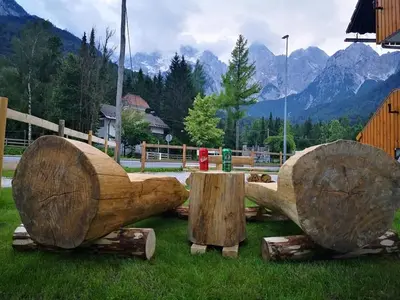 a group of logs in the grass with mountains in the background at Apartments Gaby in Gozd Martuljek