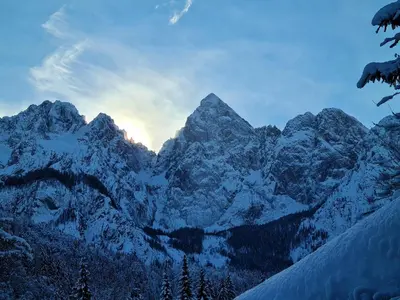 a snow covered mountain with the sun setting behind it at Apartments Gaby in Gozd Martuljek