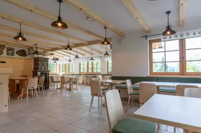 a dining room with tables and chairs and windows at Planinska koča na Uskovnici in Srednja Vas v Bohinju