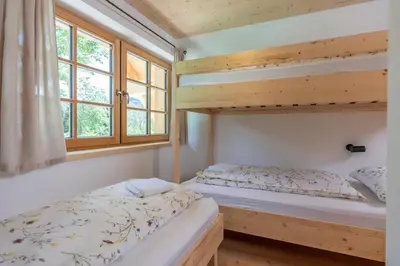 a bedroom with two bunk beds and a window at Planinska koča na Uskovnici in Srednja Vas v Bohinju