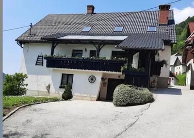 a white house with a clock on the side of it at Apartma in sobe Tanja in Podbrdo
