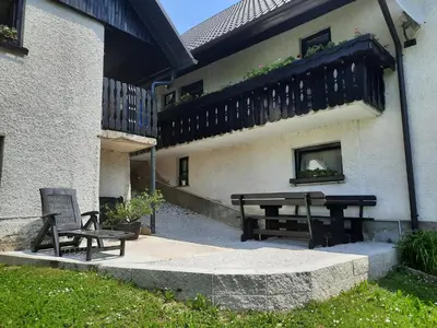 a picnic table and a bench next to a building at Apartma in sobe Tanja in Podbrdo