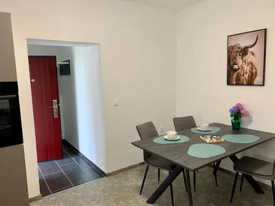 a dining room with a table and chairs and a red door at Rooms Optim in Ptuj