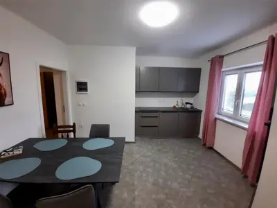 a living room with a table and a kitchen at Rooms Optim in Ptuj