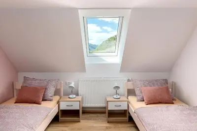 a attic bedroom with two beds and a window at Apartmaji Rupnik in Bohinjska Bistrica