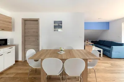 a kitchen and dining room with a wooden table and white chairs at Apartmaji Rupnik in Bohinjska Bistrica