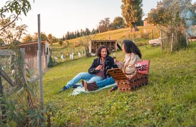 two people sitting on the grass in a field at Boutique Glamping Divja DiVine in Zgornja Korena