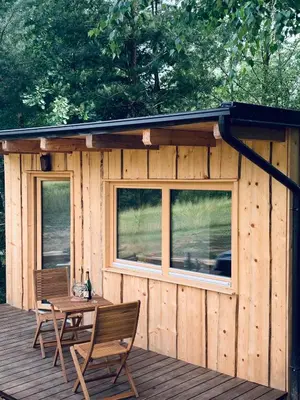 a wooden cabin with a table and chairs on a deck at Boutique Glamping Divja DiVine in Zgornja Korena