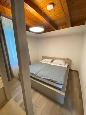 a bed in a small room with a wooden ceiling at Apartment Nona Polda in Kobarid