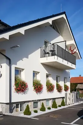 a white building with flowers on the balconies at Hiša Ančka, Šenčur - 3 min to the Airport in Kranj
