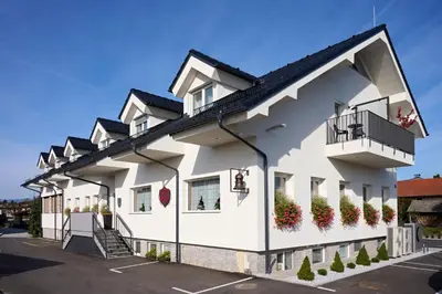 a white building with a balcony and plants at Hiša Ančka, Šenčur - 3 min to the Airport in Kranj
