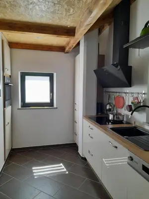 a kitchen with white cabinets and a sink and a window at Apartments Radulje Bovec in Bovec
