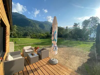 a patio with an umbrella and a chair and a couch at Apartments Radulje Bovec in Bovec