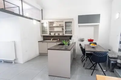 a kitchen with white cabinets and a table with chairs at Apartment THE VIEW HerMes arT in Sežana