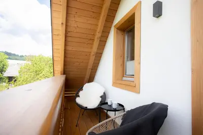 a small balcony with two chairs and a window at House Troha - Rooms & Apartments in Bled