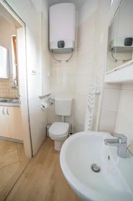 a white bathroom with a toilet and a sink at Apartma Korada in Deskle