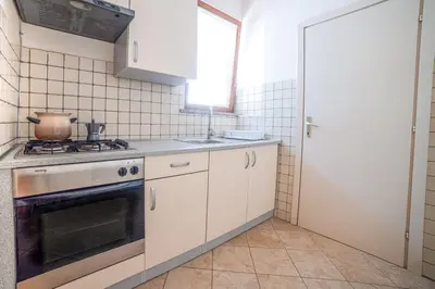 a kitchen with white cabinets and a stove and a window at Apartma Korada in Deskle