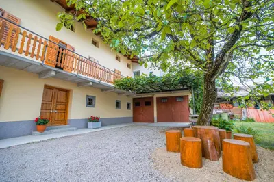 a building with a tree and some wooden stools at Apartma Korada in Deskle