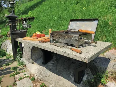 a stone table with a grill and vegetables on it at Apartma Dobra misel in Bovec