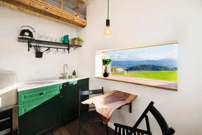 a kitchen with green cabinets and a table and a window at Lunela estate with sauna in Cerklje na Gorenjskem