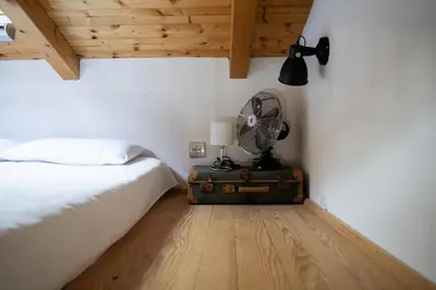 a bedroom with a bed and a fan on a suitcase at 9b-The Tiny House in Sežana
