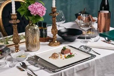 a table with a plate of food and a vase with flowers at Dvorec Gregorčič in Smarjeske Toplice