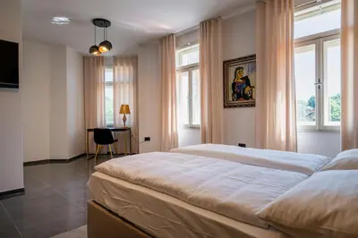 a bedroom with a large bed and two windows at Dvorec Gregorčič in Smarjeske Toplice