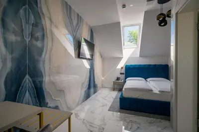 a bedroom with a blue bed and a marble wall at Dvorec Gregorčič in Smarjeske Toplice