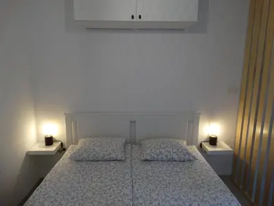 a bedroom with a white bed with two lights on it at Apartma 64 in Bovec
