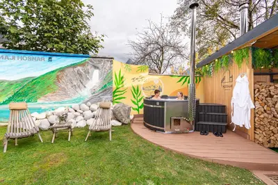 a hot tub on a deck with chairs and a wall at Penzion Hosnar, apartma Lev in Bovec