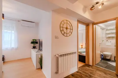 a room with a clock on the wall and a bathroom at Penzion Hosnar, apartma Lev in Bovec