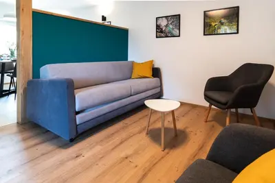 a living room with a blue couch and a chair at Garden 13 in Tolmin