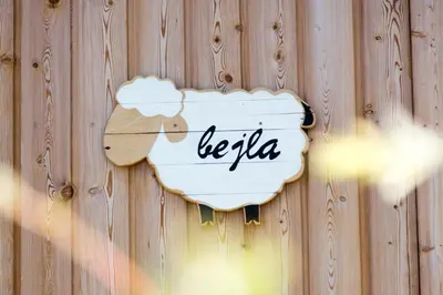 a sign on a wooden wall with the word bella at Hiša iz volne in Moravske Toplice