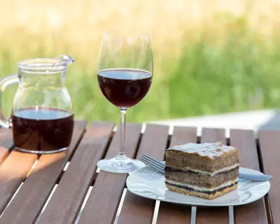 a glass of wine and a piece of cake on a table at Hiša iz volne in Moravske Toplice