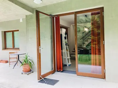 an open glass door of a house with a plant at Family House Apartma in Mozirje