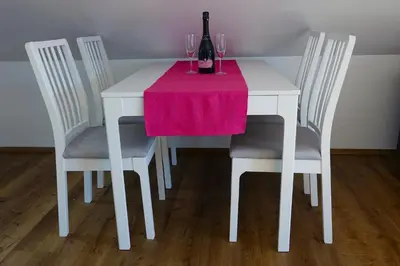 a white table with four chairs with a wine bottle on it at ININ APARTMENTS in Bled