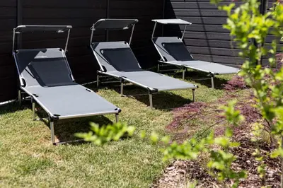 three empty lawn chairs sitting in the grass at ININ APARTMENTS in Bled