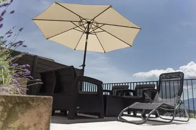 a patio with chairs and an umbrella on a balcony at ININ APARTMENTS in Bled