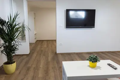 a living room with a white table and a tv on a wall at ININ APARTMENTS in Bled