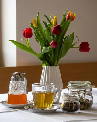a vase of flowers and a cup of tea on a table at Hiša na Vrtu in Šenčur