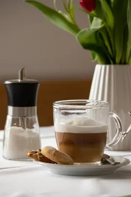 a cup of coffee and cookies on a table at Hiša na Vrtu in Šenčur