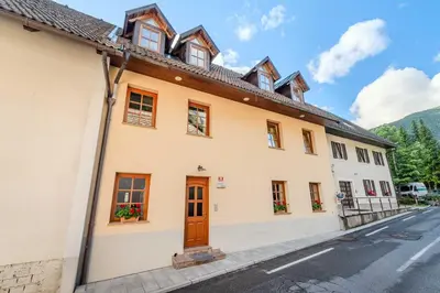 a large white building with a wooden door on a street at Apartma Miranda in Log pod Mangartom
