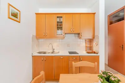 a kitchen with wooden cabinets and a wooden table at Apartma Miranda in Log pod Mangartom
