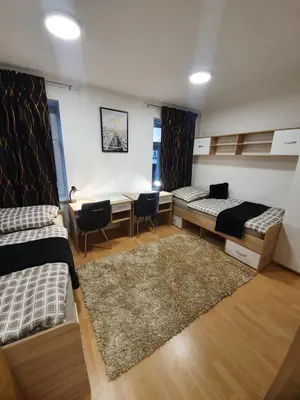a room with two beds and a desk and a table at RAILWAY STATION CITY MODERN APARTMENT in Maribor
