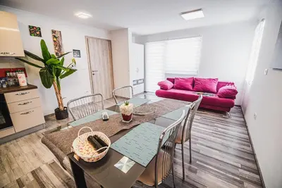 a living room with a table and a pink couch at CUDERLAND - Petra in Kobarid